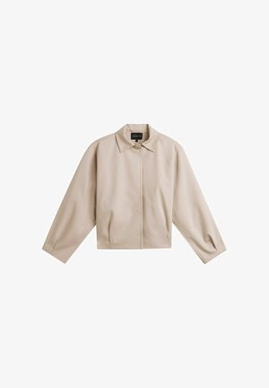 Beige cropped jack met lange mouwen, een puntige kraag, knoopsluiting aan de voorkant en zijzakken op een witte achtergrond.