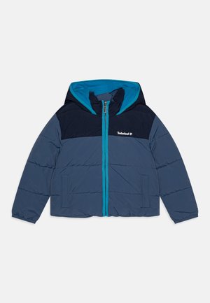 Veste rembourrée avec des panneaux bleu marine et gris, une capuche bordée de turquoise, fermeture éclair intégrale et deux poches latérales. Logo Timberland sur la poitrine.