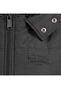 Schwarze gepolsterte Jacke mit Reißverschluss, Druckknöpfen und gesticktem Logo. Der Stoff hat eine glatte Textur mit dezentem Glanz.