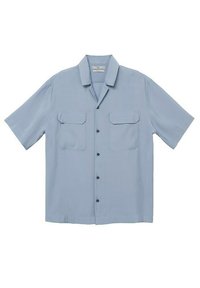 Chemise à manches courtes en tissu bleu clair. Comprend deux poches poitrine, un col, et des boutons noirs. Texture lisse, coupe décontractée.