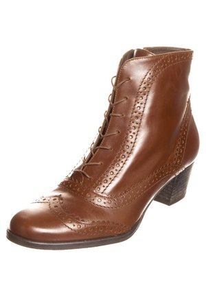 Bottine en cuir marron avec détails brogue, devant à lacets et petit talon empilé, incliné pour montrer le côté extérieur.