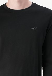 Schwarzes Langarm-T-Shirt aus weicher Baumwolle, mit rundem Ausschnitt und kleinem grauen Logo "JOOP! JEANS" auf der Brust.