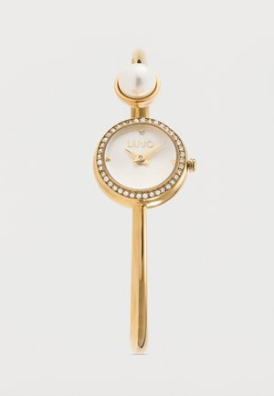 Montre-bracelet ton or avec lunette ornée de cristaux, cadran blanc, aiguilles dorées et une grande perle décorative au fermoir.