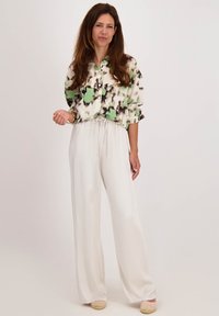 Overhemd met een groene en zwarte abstracte print, gecombineerd met witte hoge wijde broek met elastische taille.