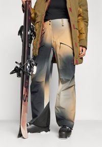 Síszárak, fokozatos bézses-fekete színben, számos cipzáras zsebbel, vízálló anyagból készült, megerősített szegéllyel. Fekete sícipő és snowboard is tartozik hozzá.