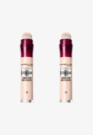 Correcteur anti-âge instantané Maybelline dans un flacon cylindrique. Il dispose d'un applicateur en éponge arrondi. Couleur beige clair avec un capuchon rouge foncé.