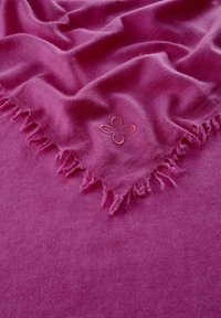 Écharpe fuchsia en matière douce avec un bord frangé et un motif de fleur brodé dans une teinte plus claire. Texture lisse.