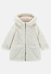 Biała sztuczna futrzana kurtka z kapturem, z zapięciem na suwak z przodu, bocznymi kieszeniami oraz miękką podszewką. Okrągły kształt i casualowy styl.