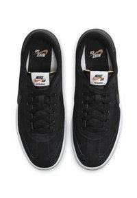 Mustat mokkanahkaiset tennarit, joissa on valkoiset kumipohjat. Niissä on mustat nauhat ja oransseilla yksityiskohdilla varustetut merkitty sisäpohjat. Klassinen muotoilu.