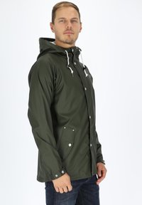Olive green waterproof jacket with a hood, snap buttons, adjustable drawstrings, and two side pockets. Smooth texture and casual design.
