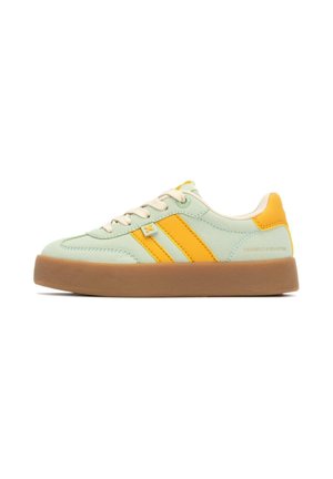 Zapatilla verde claro con acentos amarillos, dos rayas amarillas, cordones beige y suela de goma marrón. Textura suave con forma redondeada.