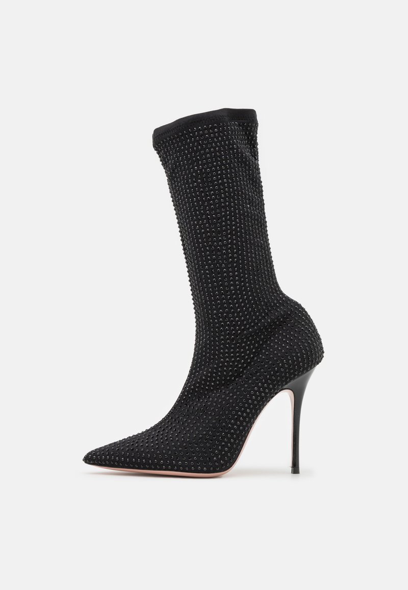 Zwarte hoge haklaarzen met een spitse neus en een sokachtige silhouet. Geweven stof versierd met kleine kralen. Stiletto hak ontwerp.