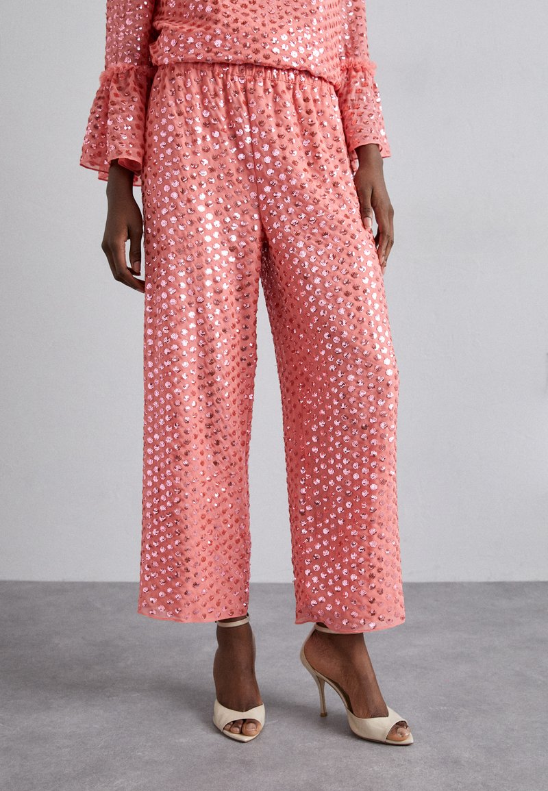 Pink sequined two-piece outfit featuring wide-leg pants and a top with ruffled sleeves, showcasing a shimmering, textured surface.