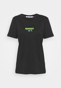 Černé tričko s krátkým rukávem vyrobené ze 100% bavlny. Má zelený a stříbrný logo detail na prsou. Klasický kulatý výstřih a volný střih.