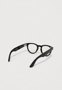 Sorte katteøje solbriller med transparente linser, blank ramme og sølvdetaljer på stænger. Glat tekstur og stilfuldt design.