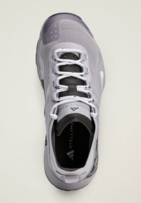 Světle šedý sportovní boty s mesh svrškem, bílými tkaničkami, černými detaily a texturovanou podrážkou s vzorovaným bočním designem.
