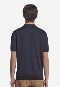 Marinblå polo-shirt med kort ärm i texturerad väv, ribbad krage och manschetter. Rakt nederkant, minimalistisk design och ingen synlig branding.