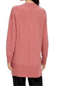 Pull à manches longues en tissu rose doux, avec un ourlet et des poignets côtelés, et une coupe décontractée avec une couture centrale au dos.