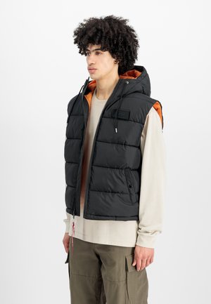 Schwarze Daunenweste mit Kapuze und orangefarbigem Innenfutter. Sie hat einen Reißverschluss, Patch-Details und Zugbänder zur Anpassung.