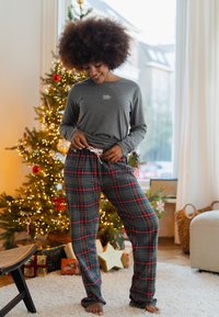 Grijze longsleeve met de tekst "Jolly". Geruite pyjamabroek in blauw, rood en groen. Zachte stof met een elastische tailleband en trekkoord.