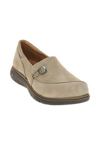Beige suede slip-on shoe with a rounded toe, decorative metal accent, and flexible black rubber sole. Features stitching detail along the seams.