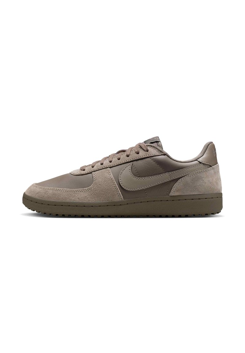 Lys brun sneaker med en overdel i ruskind og læder, afrundet tå, snørebåndslukning og struktureret gummisål. Har et diskret logo.