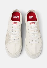 Weiße Sneakers mit Schnürsenkeln, ausgestattet mit roten Innensohlen, die mit "CAMPER" und "TWINS" beschriftet sind. Glatte Ledertextur und minimalistisches Design.