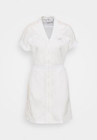 Biała sukienka z krótkim rękawem i zamkiem błyskawicznym, z elastycznym paskiem w talii, logo Adidas na klatce piersiowej oraz beżowe paski z małymi kropkami na ramionach i bokach.