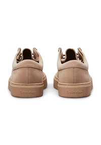 Sneaker in suede beige con una finitura liscia, design senza lacci e un marchio discreto sul tallone. Punta arrotondata e colletto imbottito.