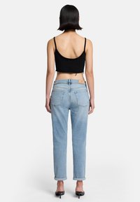 Jeans in denim azzurro chiaro con gamba affusolata e orli risvoltati, dotati di una toppa in pelle sul retro e di un fit casual e rilassato.