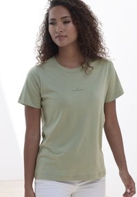 Light green cotton t-shirt with short sleeves and a round neck. Features a subtle "Copenhagen" logo printed on the front.