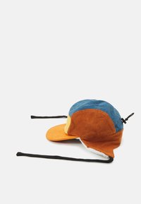 Casquette en velours côtelé avec un design multicolore en bleu, orange et jaune. Elle présente un bord courbé et des sangles ajustables pour un maintien sécurisé.