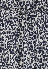 Tissu blanc avec un motif léopard irrégulier en noir et gris, accompagné d'une fine ceinture en tissu assorti nouée à la taille.