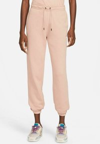 Ljusrosa sweatpants med elastiska muddar och dragsko i midjan. Mjukt material med sidodetaljer, kombinerat med flerfärdade sneakers.