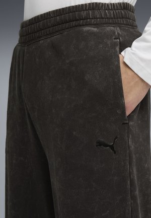 Sorte sweatpants lavet af blødt stof med en struktureret overflade. De har en elastisk talje og sidelommer, samt en broderet logo.