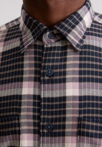 Kariertes Hemd mit Knopfleiste, das einen marineblauen Hintergrund mit rosa und beigen Karos zeigt, gefertigt aus einem strukturierten Stoff, mit Standardkragen und schwarzen Knöpfen.