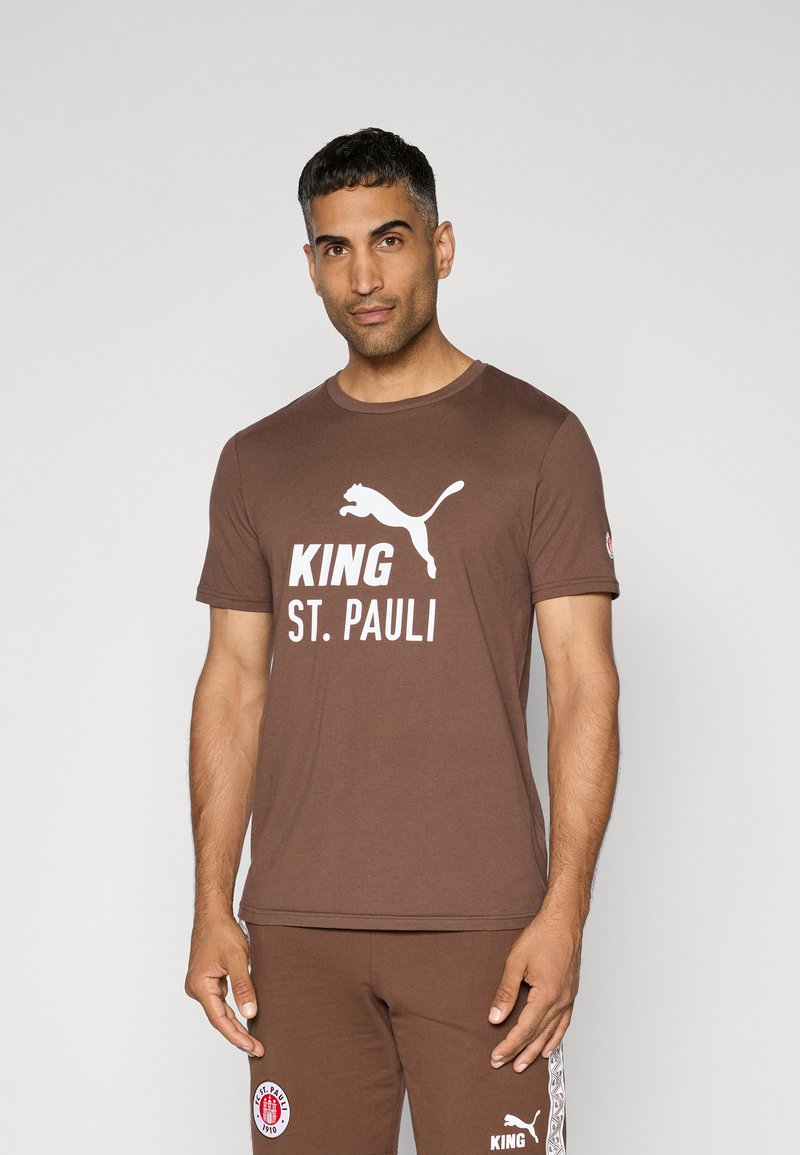 Brun bomulds t-shirt med rund hals, der har hvid tekst "KING" og "ST. PAULI" samt et hvidt Puma-logo på fronten.
