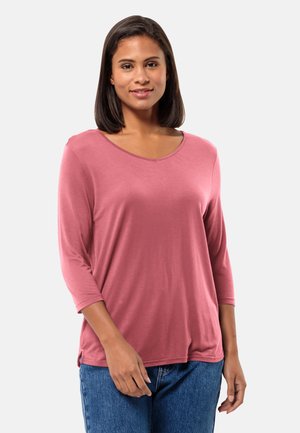 Roze langoe mouwtop met een V-hals, zachte textuur en zijspleten, gecombineerd met blauwe jeans.