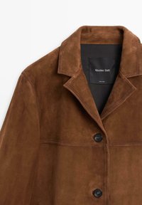 Bruine suède jack met een kraag, voorzien van zwarte knopen en een gestikte horizontale naad. Label aan de binnenkant toont "Massimo Dutti."