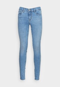 Jeans ajustados de mezclilla de color azul claro con cintura media, que presentan bolsillos delanteros, cierre de botón y una textura suave.