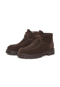 Bocanci din suede maro cu vârful rotund, detalii cusute, sistem de închidere cu șireturi și o talpă din cauciuc robustă. Textură netedă și design clasic.