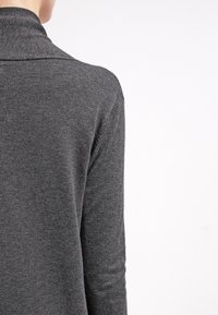 Suéter gris de punto con cuello alto, que presenta una textura suave y un diseño ajustado, mostrando la vista posterior y las mangas largas.