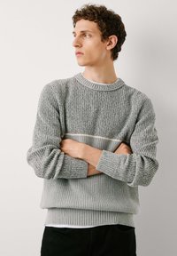 Grauer Strickpullover mit strukturiertem Muster, rundem Ausschnitt und gerippten Bündchen und Saum. Ein subtiler heller Streifen verläuft horizontal über die Brust.