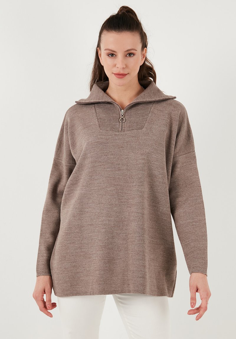 Brauner, übergroßer Pullover mit Reißverschlusskragen, gerippten Details und langen Ärmeln. Weicher Stoff und seitliche Schlitze am Saum für mehr Bewegungsfreiheit.
