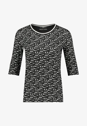Chemise cintrée noire et blanche à manches trois-quarts, col rond et motif abstrait de lettres en bloc couvrant toute la surface.