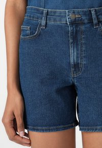 Dark blue denim shorts with a classic five-pocket design, featuring a button closure and visible stitching along the hem.