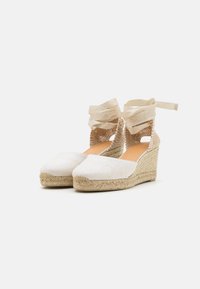 Bílé plátěné espadrilky s vyvýšenou podešví, s pletenými slámovými podrážkami, texturovanými otevřenými tkaninami po stranách a stužkami na kotníky.