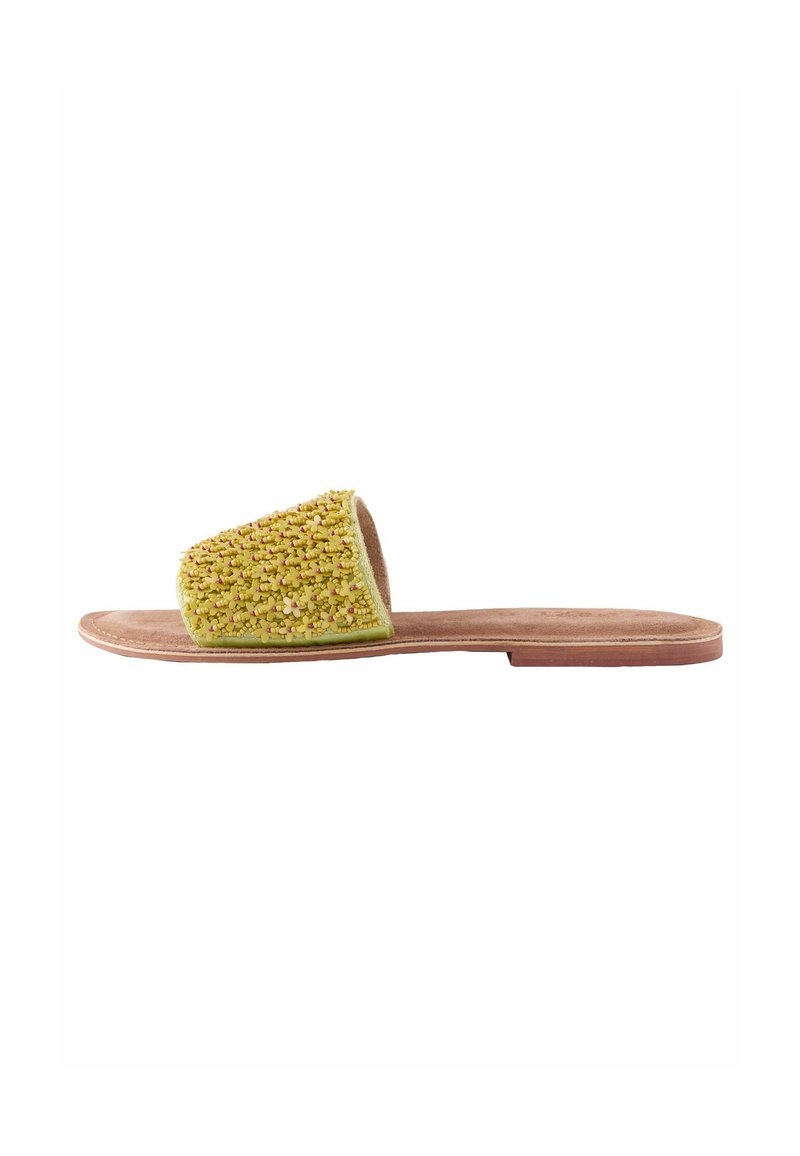 Sandalia tipo slide con parte superior de tejido amarillo texturizado, suela plana marrón y diseño de punta abierta. Presenta una plantilla suave y un estilo minimalista.