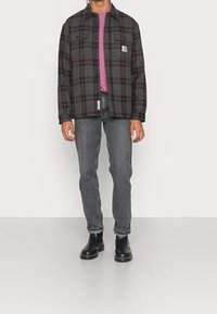 Rutet flannel skjorte i sort og grå, med to brystlommer, lagd over en lyserød T-shirt med sorte jeans og sorte chelsea-boots.