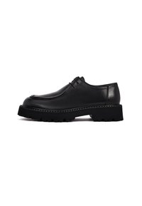 Zapatos de cuero negro con punta redondeada, parte superior texturizada y suela de goma gruesa y estriada. Presentan un cordón mínimo y un acabado suave.